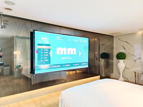 a large screen tv on a wall in a bedroom at MMMotel in Taoyuan