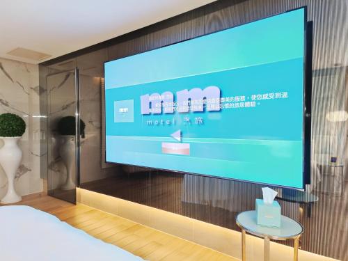 TV de pantalla grande en la pared de una habitación en MMMotel, en Taoyuan