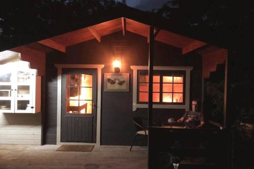 a man sitting in front of a house at night at Unique Tiny House near 3 Peaks - The ZedShed in High Bentham