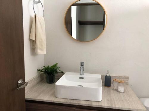 uma casa de banho com um lavatório branco e um espelho. em Velamar, casa con alberca y asador em Miramar