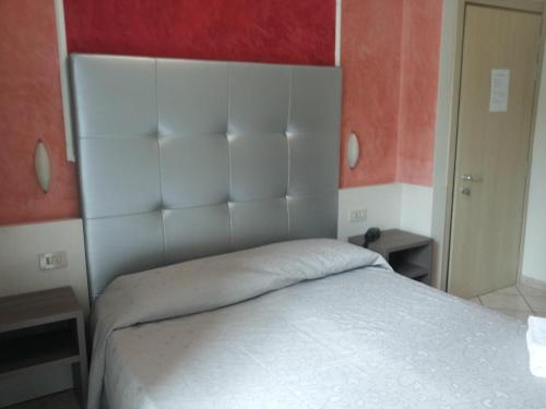 una camera con un letto bianco con una parete rossa di Hotel Le Querce a Milano