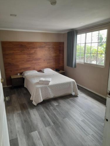 a bedroom with a large bed with a wooden headboard at Hotel Dunas in Panama City