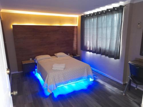 a bedroom with a bed with blue lights on it at Hotel Dunas in Panama City