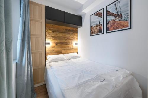 una camera con un letto bianco con due immagini sul muro di Prime Apartments - Studio a Sopot