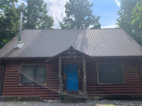 Cette petite cabane en rondins est dotée d'une porte bleue. dans l'établissement Barefoot Cabin, 
