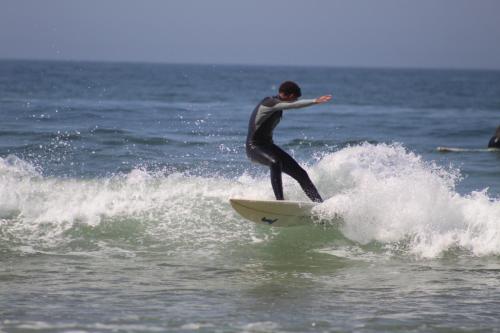 un hombre montando una ola en una tabla de surf en el océano en Welle Surf Morocco, en Taghazout