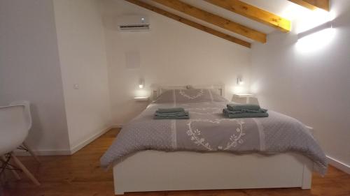 a white bedroom with a bed with two lamps at Charm studio in Bombarral