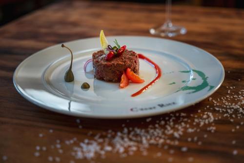 eine weiße Platte mit einem Stück Essen auf dem Tisch in der Unterkunft Kulinarik & Geniesser Hôtel STRAUSS in Fiesch