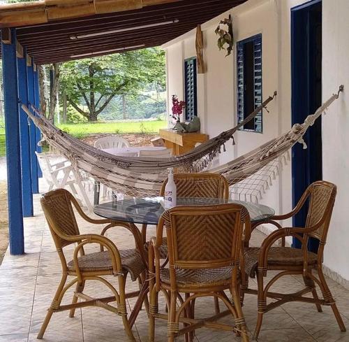 a hammock on a porch with a table and chairs at Sítio Cantinho da Cachoeira in Guapé
