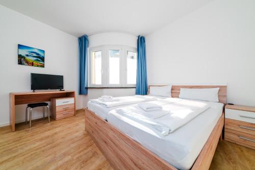 Dormitorio con cama, escritorio y TV en G & L City Rooms, en Dortmund