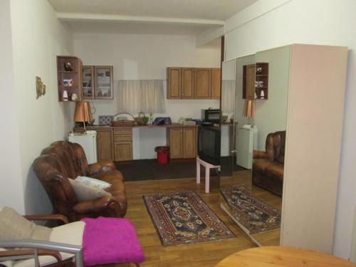 a living room with leather chairs and a kitchen at Pension Werner Nagel in Wewelsfleth
