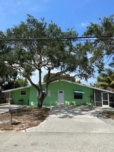 een groen gebouw met een boom ervoor bij Newly remodeled, Cozy Cottage in North Palm Beach in North Palm Beach