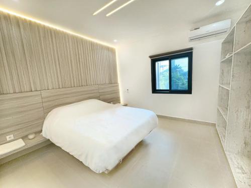 a bedroom with a white bed and a window at Appartement Palms Abidjan in Abidjan