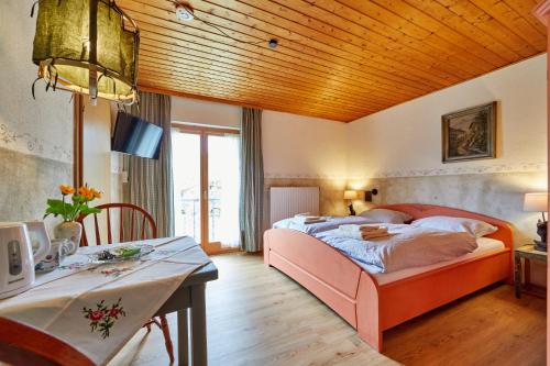 Un dormitorio con una cama grande y una mesa con escritorio Sidx Sidx en Gästehaus Eder Oberammergau en Oberammergau