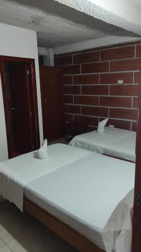 2 Betten in einem Zimmer mit Ziegelwand in der Unterkunft Hospedaje Norcasia in Norcasia