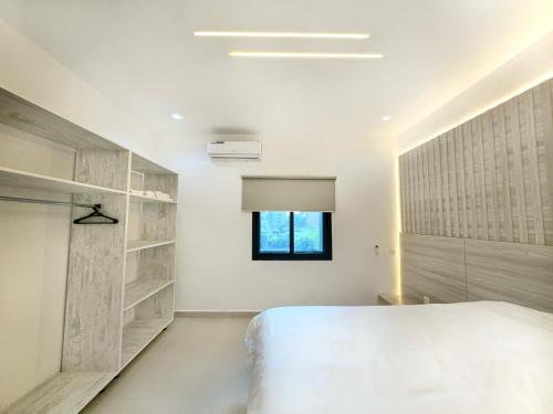 Appartement Palms Abidjan في أبيدجان: غرفة نوم بسرير ابيض ونافذة