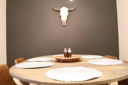 a wooden table with plates and a bull skull on the wall at Cowboy Den-Hot Tub-Game Room-Pet Friendly-No Pet Fees! in Albuquerque