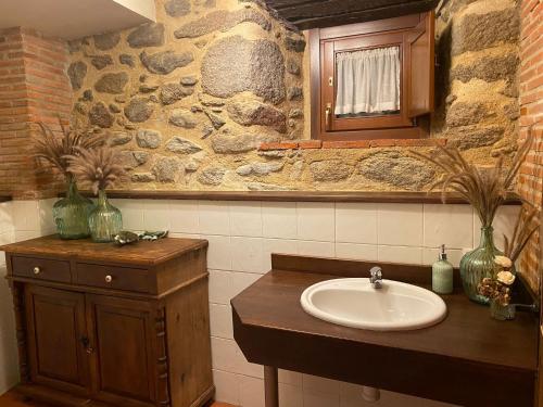a bathroom with a sink and a stone wall at La Clerecia de Ledesma in Ledesma