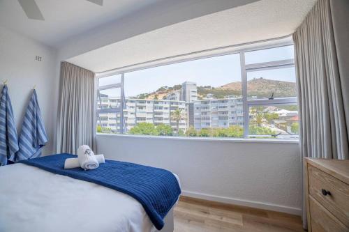 a bedroom with a large window with a teddy bear on a bed at Greenpoint Emerald in Cape Town