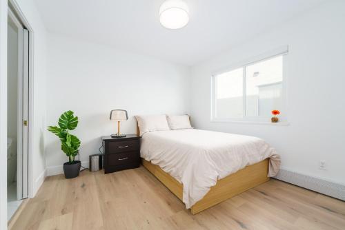 a white bedroom with a bed and a window at Steveston Village Bed and Breakfast in Richmond