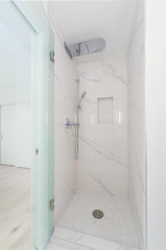 a white bathroom with a shower with a glass door at Steveston Village Bed and Breakfast in Richmond