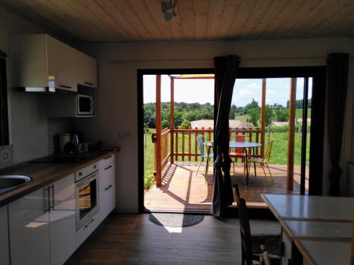 eine Küche mit einer Tür, die auf eine Terrasse mit einem Tisch führt in der Unterkunft Maison sur pilotis in Saint-Palais