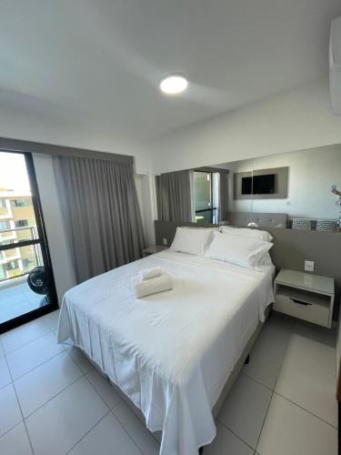 een slaapkamer met een groot wit bed en 2 handdoeken bij Flat com vista para piscina principal in Ipojuca