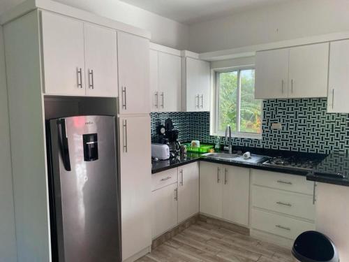 La cuisine est équipée de placards blancs et d'un réfrigérateur en acier inoxydable. dans l'établissement Vasquez apartamentos, à La Piña
