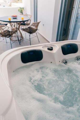 a bathtub filled with water with a table and chairs at Orion Suite & Apartments in Donoussa