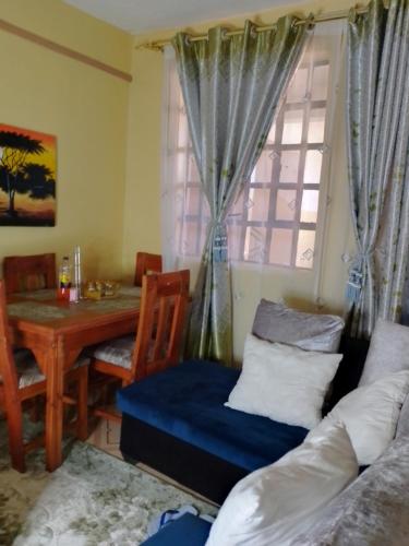 salon z kanapą, stołem i oknem w obiekcie IMMARA BNB w mieście Nakuru