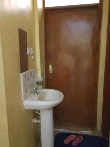 ein Badezimmer mit einem Waschbecken und einer Holztür in der Unterkunft IMMARA BNB in Nakuru
