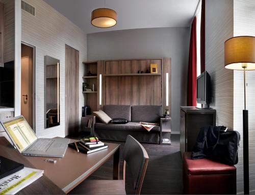 a living room with a couch and a desk with a laptop at Aparthotel Adagio Strasbourg Place Kleber in Strasbourg