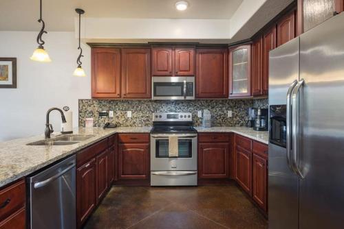 una cocina con armarios de madera y electrodomésticos de acero inoxidable en Luxury Downtown Rental (Hot Tub/Pet Friendly) - La Dolce Vita Villas #8, en Moab
