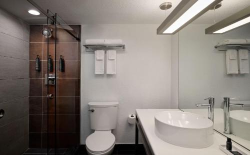 a white bathroom with a toilet and a sink at Aloft Miami Dadeland in Kendall