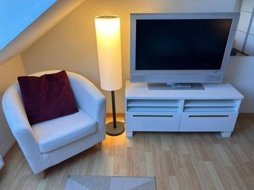 ein Wohnzimmer mit einem TV, einem Stuhl und einer Lampe in der Unterkunft Ferienwohnung Bernsteinwind in Graal-Müritz