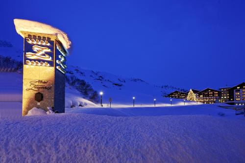 a building covered in snow at night at Hotel Zürserhof in Zürs am Arlberg