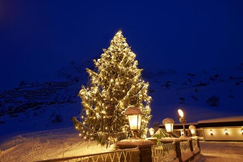 a christmas tree with lights in the snow at night at Hotel Zürserhof in Zürs am Arlberg