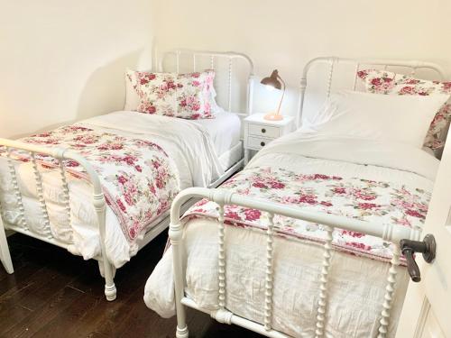 two twin beds in a room with flowers at Plantation House Bed & Breakfast in Port Hope