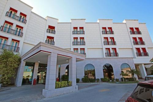 a large white building with red windows at Hotel Colón Plaza Business Class in Nuevo Laredo