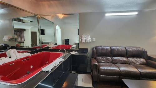 baño con bañera roja y sofá de cuero en Scottish Inn & Suites Sam Houston Parkway, en Houston