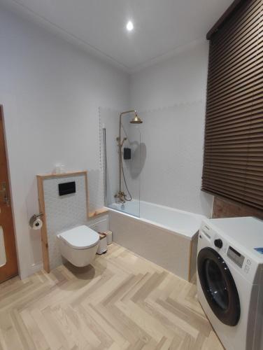 a bathroom with a tub and a toilet and a shower at Apartments PSD - Anny Łajming 1D in Słupsk