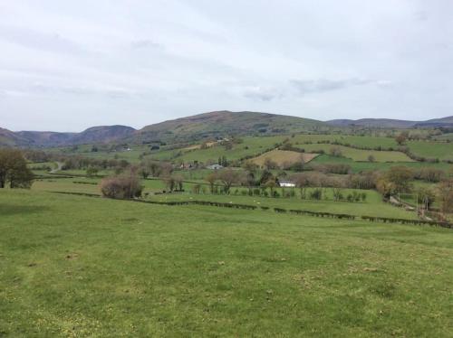 a green field with hills in the distance at The Retreat in Llanrhaeadr-ym-Mochnant