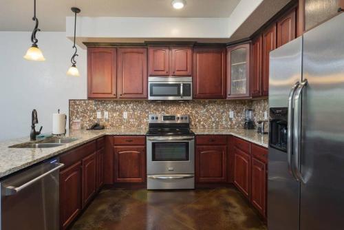 eine Küche mit Holzschränken und Geräten aus Edelstahl in der Unterkunft Luxury Downtown Rental (Hot Tub/Pet Friendly) - La Dolce Vita Villas #9 in Moab