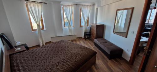 a bedroom with a bed and a couch and windows at Grand Monastery 3 Apartment 10 in Pamporovo