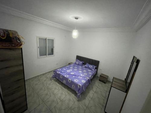 a bedroom with a purple bed and a window at DIaR MAHER in Al Maqārisah