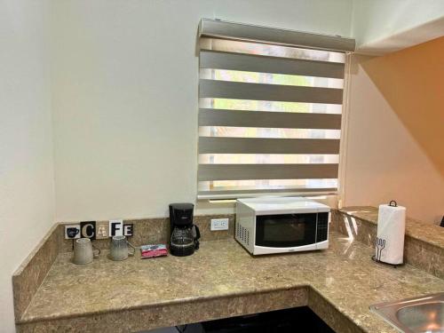 a microwave on a kitchen counter with a window at Encantador loft 1 frente a plaza in Loreto