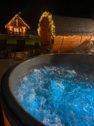 een hot tub met blauw water in een tuin 's nachts bij Leśna Osada -Dominikowo -sauna , balia in Dominikowo