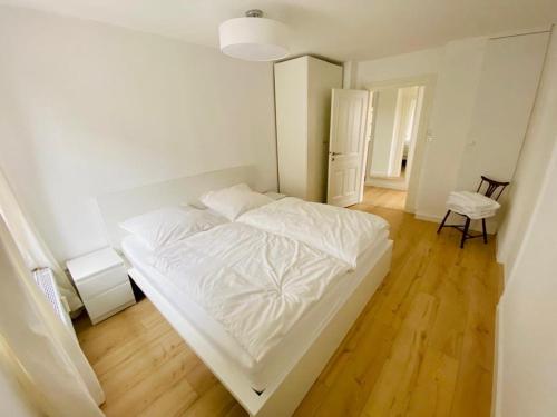 uma cama branca num quarto com piso em madeira em Cute Apartment - Detmold city center - large kitchen, bath, south facing balcony - free parking and wifi em Detmold
