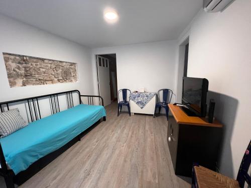 Schlafzimmer mit einem Bett, einem TV und einem Tisch in der Unterkunft Apartamento com pátio em frente praia in Paço de Arcos