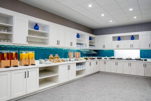 a large kitchen with white cabinets and blue accents at Hyatt Place St Augustine Vilano Beach in Saint Augustine